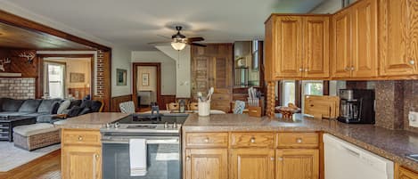 A modern kitchen with wooden cabinets, a stainless steel stove, and a granite countertop.