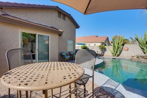 A patio with a table and chairs, a swimming pool, and a house with a tiled roof. - 3 Mi to Surprise Stadium! Extended Poolside Stay (Surprise)