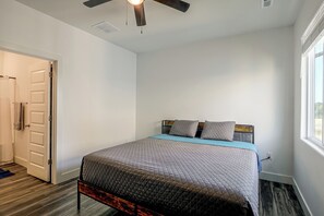 Une chambre à coucher avec un lit, un ventilateur de plafond, une fenêtre et une porte.