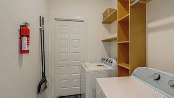 A laundry room with a washing machine, a dryer, a fire extinguisher, and a broom.