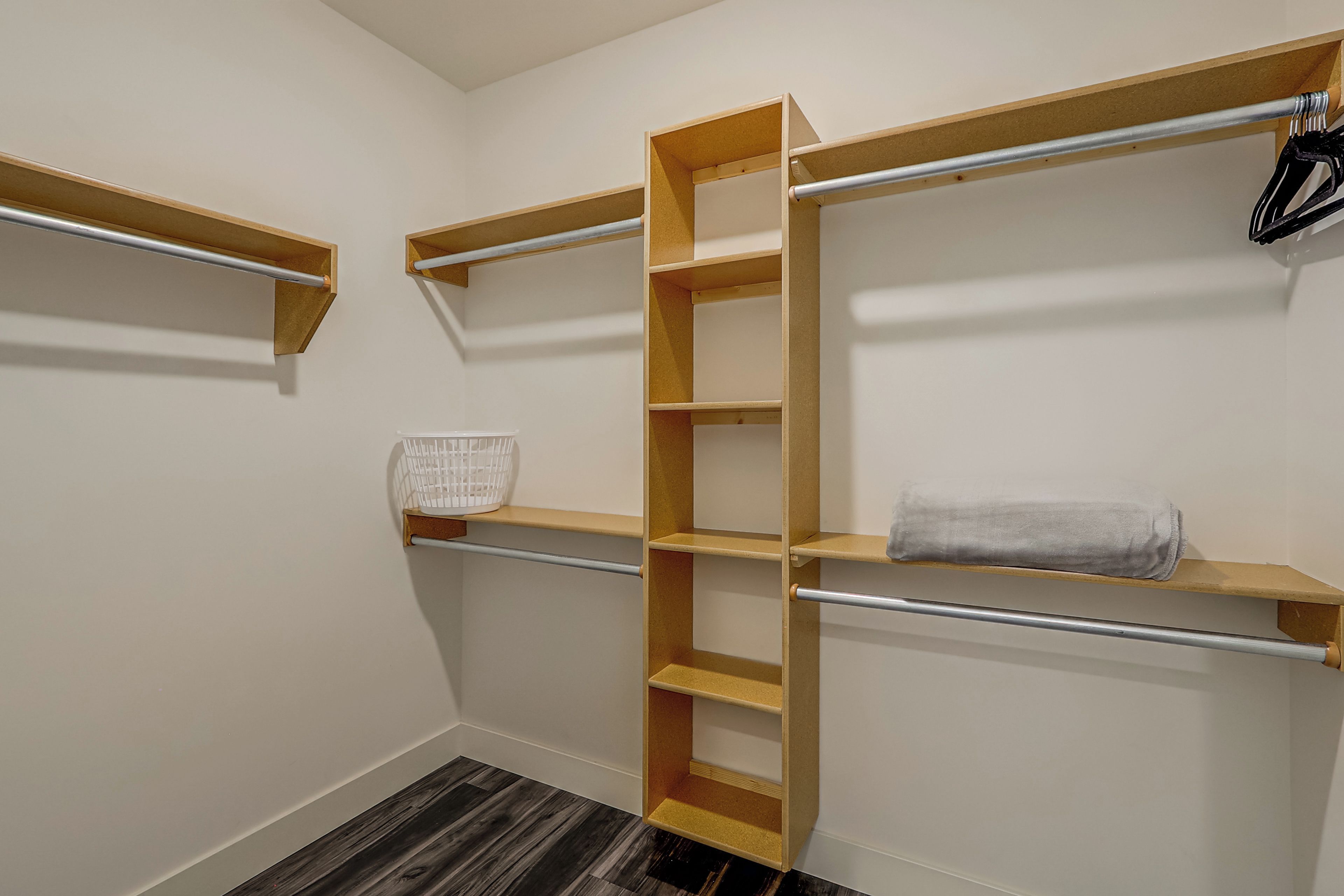A walk-in closet with wooden shelves and a metal rod for hanging items.