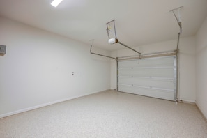Eine Garage mit geschlossenem Garagentor, Leuchtstofflampen und einem an der Decke befestigten Projektor.