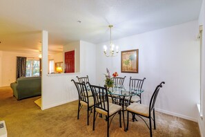 A dining area with a glass table and chairs, a chandelier, and a painting on the wall. - Pool Access! Kissimmee Gem, Enclosed Patio (Kissimmee)