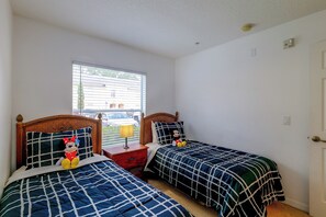 A bedroom with two beds, a nightstand, a lamp, and a window with blinds. - Pool Access! Kissimmee Gem, Enclosed Patio (Kissimmee)