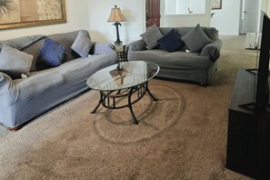 A living room with two sofas, a coffee table, a lamp, and a television. - Pool Access! Kissimmee Gem, Enclosed Patio (Kissimmee)