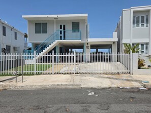 A two-story residential building with a white exterior, a blue staircase, and a white fence. - Charming 3-Bedroom House in Monte Vista Fajardo, Puerto Rico (Fajardo city)
