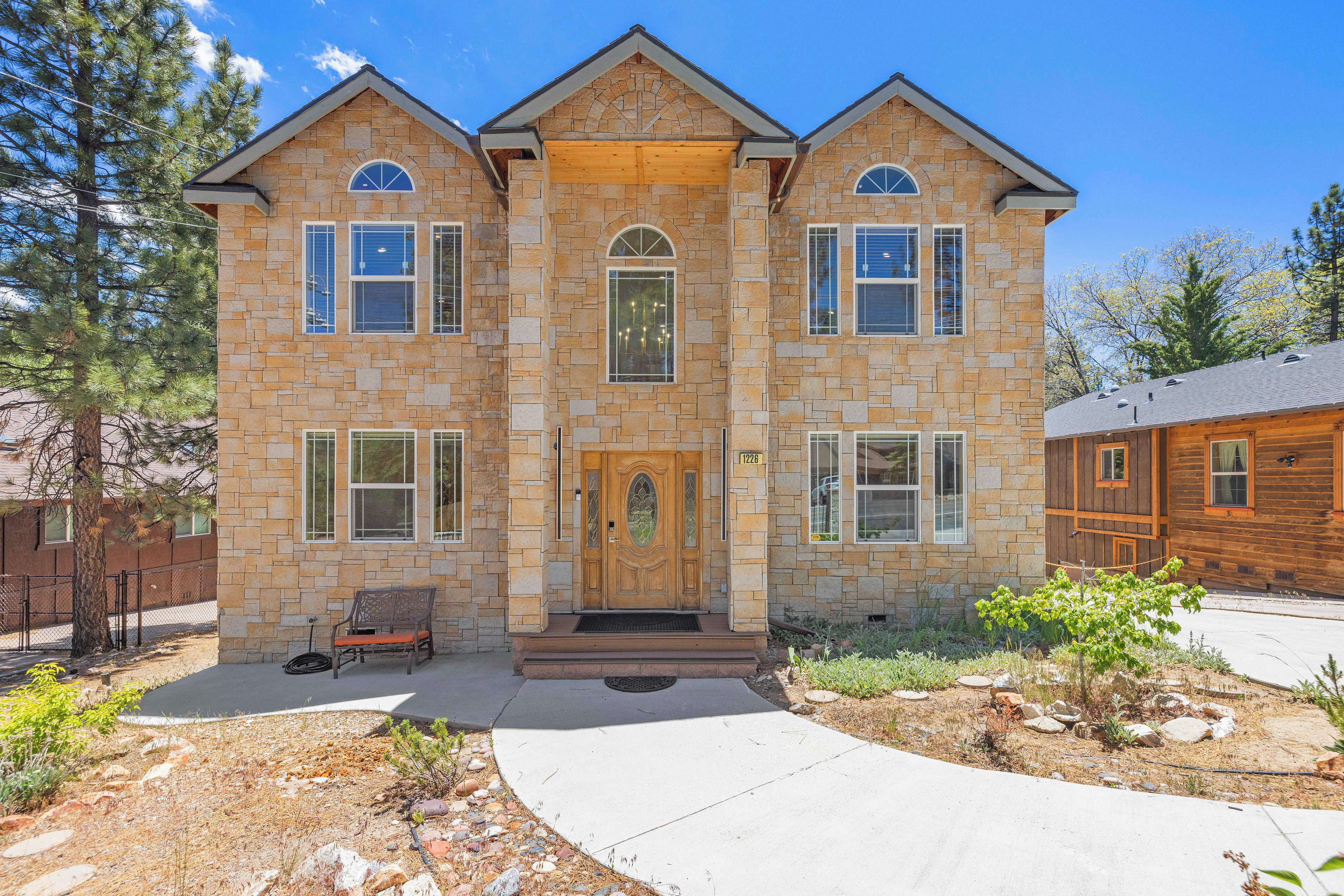 A three-story stone house with a central entrance, multiple windows, and a wooden porch.