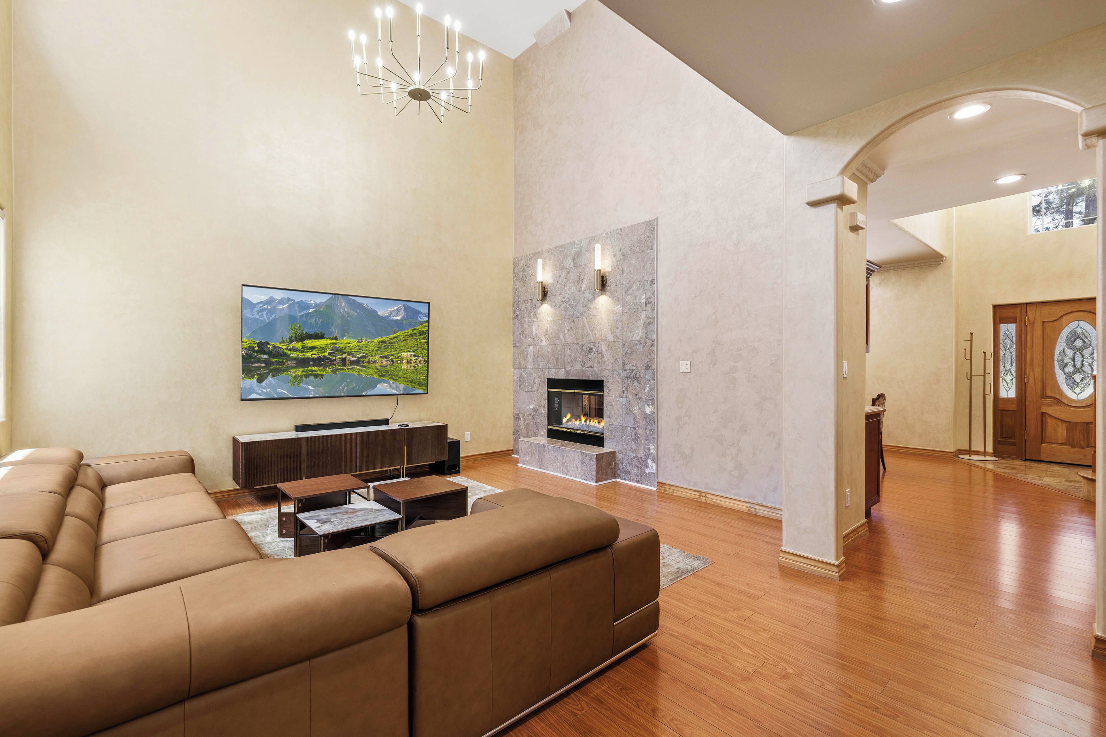 A spacious living room with a large flat-screen TV, a fireplace, and a modern sofa set.