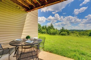 Eine Terrasse im Freien mit Esstisch, umgeben von Grünpflanzen und blauem Himmel.
