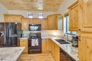 A kitchen with wooden cabinets, stainless steel appliances, a marble countertop, and a wooden floor. - Torreon Mountain Retreat - Golf, Hike, Relax (Show Low)