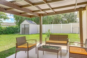 Eine Terrasse im Freien mit Korbmöbeln und einem kleinen Schuppen im Hintergrund.