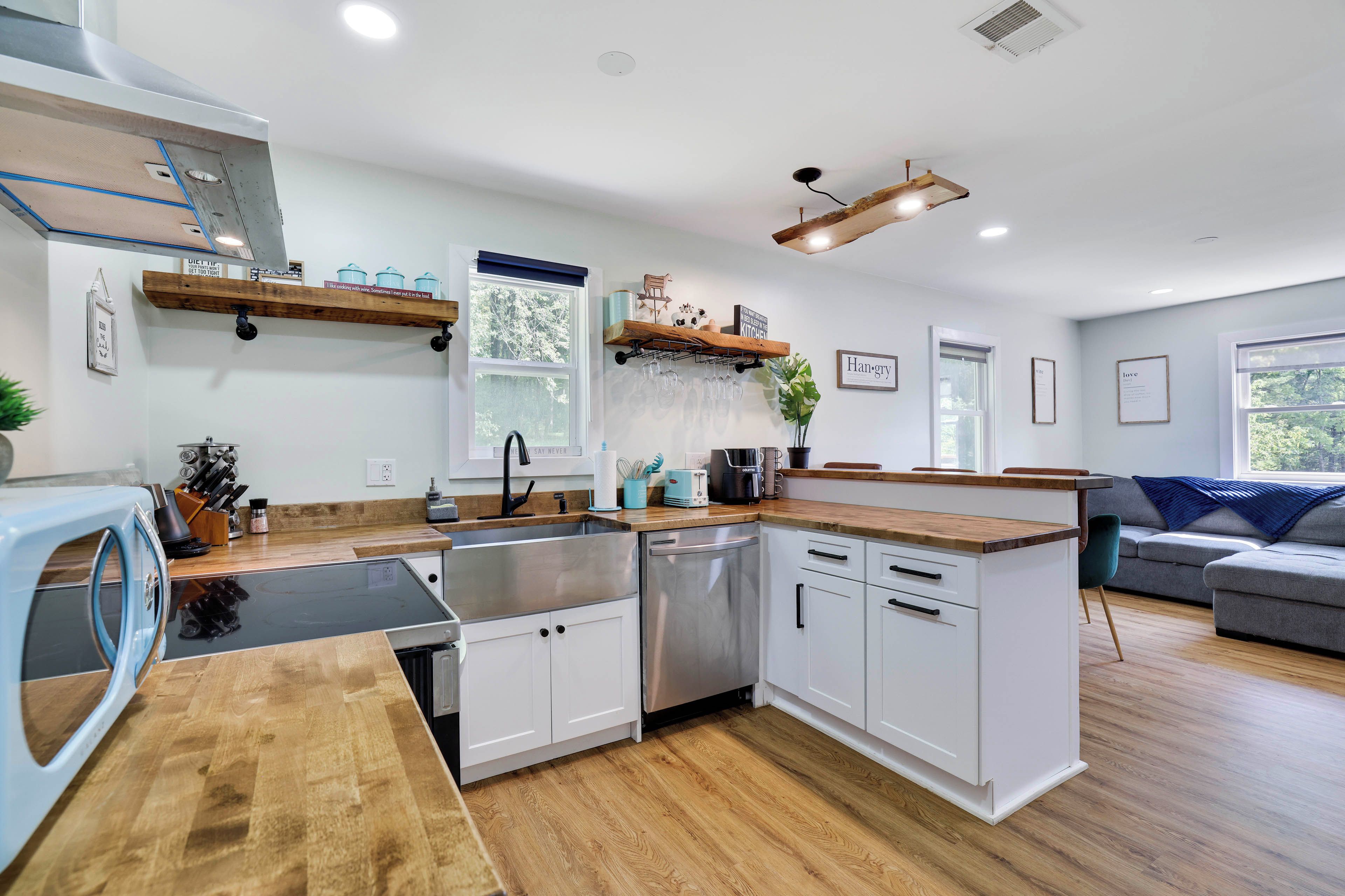 Cocina moderna con lavavajillas, pileta y encimeras de madera. Posee alacenas empotradas y una ventana con vista a árboles.