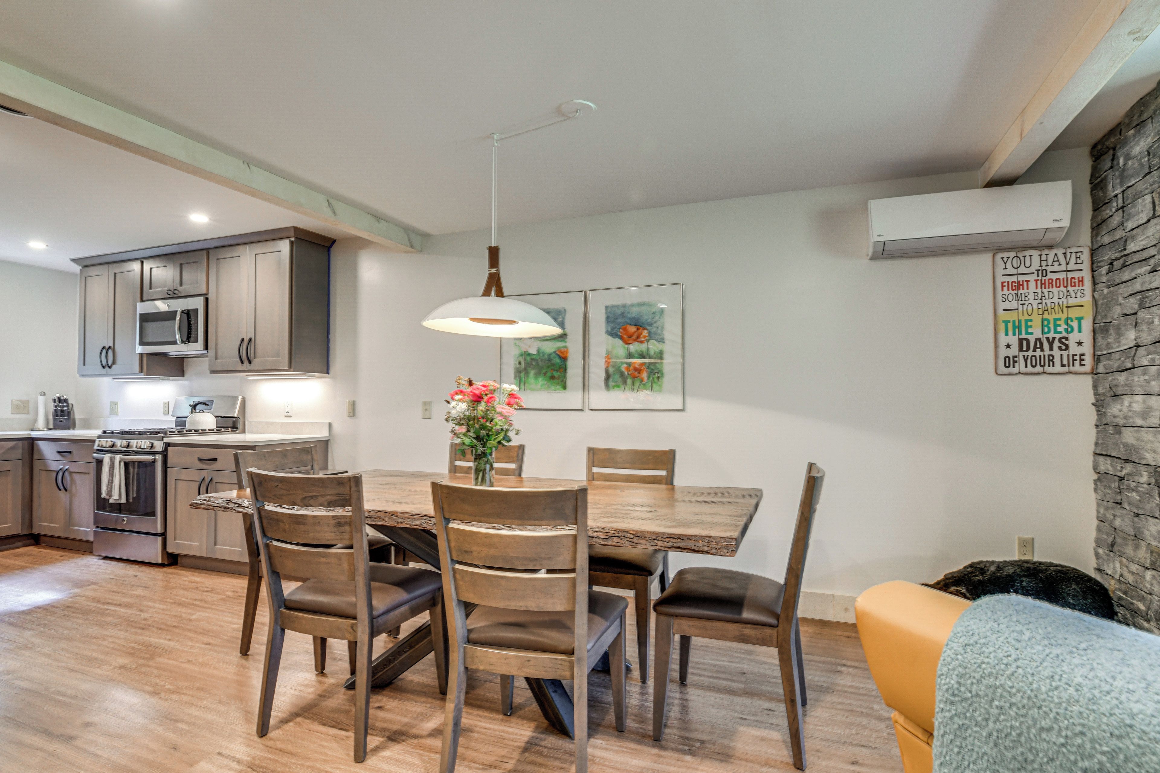 A modern kitchen with stainless steel appliances, wooden cabinets, and a dining area with a wooden table and chairs.