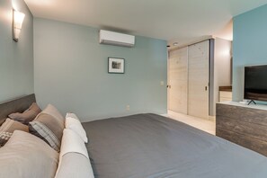 A bedroom with a bed, a dresser, a TV, a wardrobe, and an air conditioning unit. - Stowe Ski, Bike & Hike Condo w/ Pools & Clubhouse (Stowe)