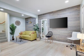 A modern living room with a sofa, a coffee table, a TV, a chair, and a staircase. - Tannersville Mtn Escape: Ski, Hike & Shop! (Tannersville)
