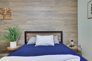 A bedroom with a bed, a nightstand, a lamp, a potted plant, and a wall-mounted map. - Tannersville Mtn Escape: Ski, Hike & Shop! (Tannersville)