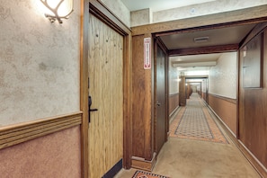 Ein Hotelkorridor mit Holztüren, einem Feuerschutztürschild und einem gemusterten Teppich.