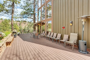 Eine Terrasse im Freien mit Holzboden, Metallstühlen und einem Grill.