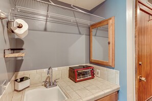 Un bagno con lavandino, specchio, porta asciugamani e un tostapane rosso.