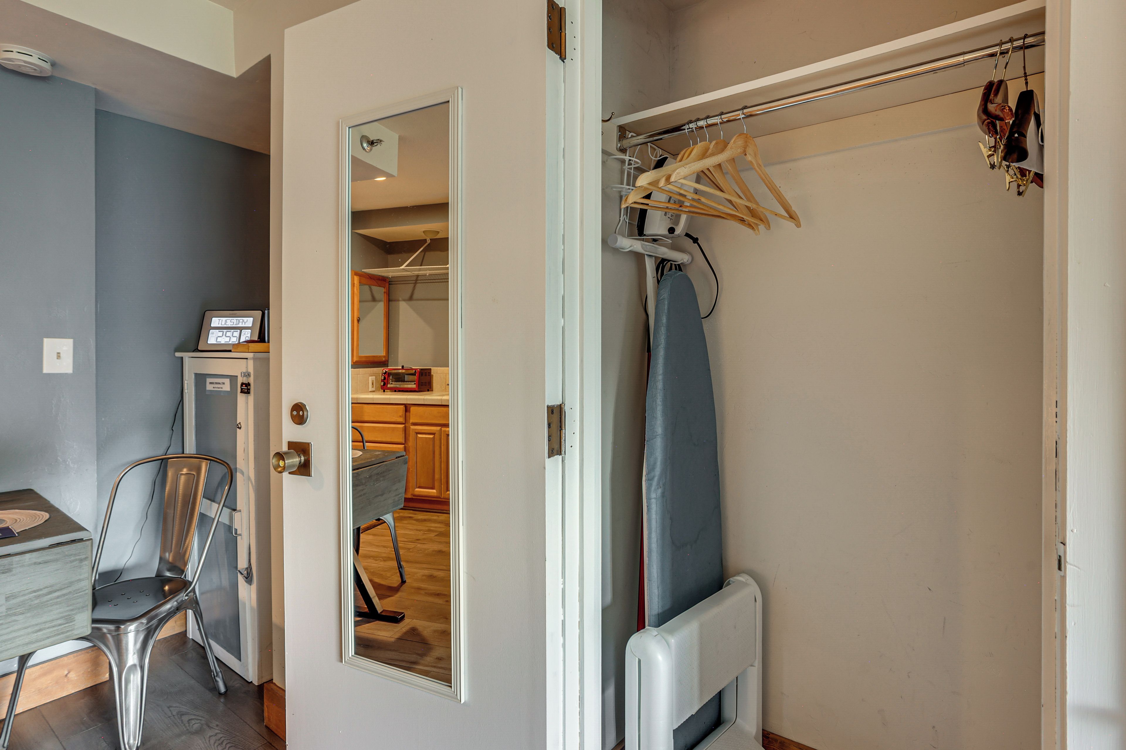A room with a door leading to a kitchen area, a wheelchair, and a coat rack with hangers.