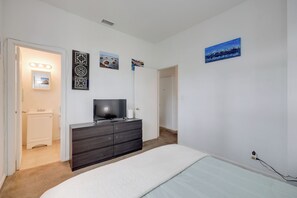 A bedroom with a bed, a dresser, a television, and artwork on the wall. - Stroll to Arts & Eats! Jacksonville Condo (Jacksonville)