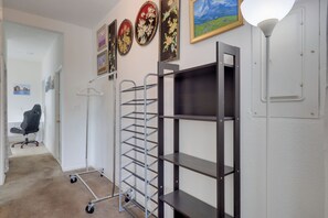 A room with a metal shelving unit, a desk chair, a coat rack, and a wall-mounted lamp. - Stroll to Arts & Eats! Jacksonville Condo (Jacksonville)