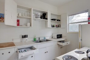 A compact kitchen with white cabinets, a microwave, a stove, and a window with a view of the outside. - Stroll to Arts & Eats! Jacksonville Condo (Jacksonville)