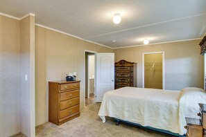 Une chambre à coucher comprenant un lit, une commode, une armoire et une porte donnant sur une autre pièce.