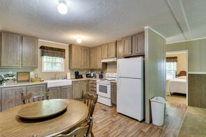 A kitchen with wooden cabinets, a dining table with chairs, a refrigerator, and a stove. - Quiet Extended Stay Near Rivanna River (Palmyra)