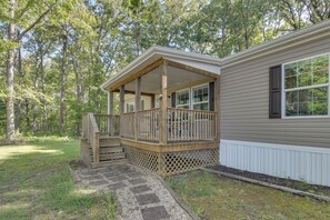 A single-story house with a covered porch, a stone pathway leading to the entrance, and a forested backdrop. - Quiet Extended Stay Near Rivanna River (Palmyra)