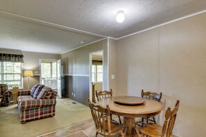 A living room with a plaid sofa, a dining table with chairs, a refrigerator, and a lamp. - Quiet Extended Stay Near Rivanna River (Palmyra)