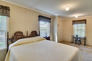 A bedroom with a large bed, two windows with curtains, a desk with a chair, and a ceiling light. - Quiet Extended Stay Near Rivanna River (Palmyra)