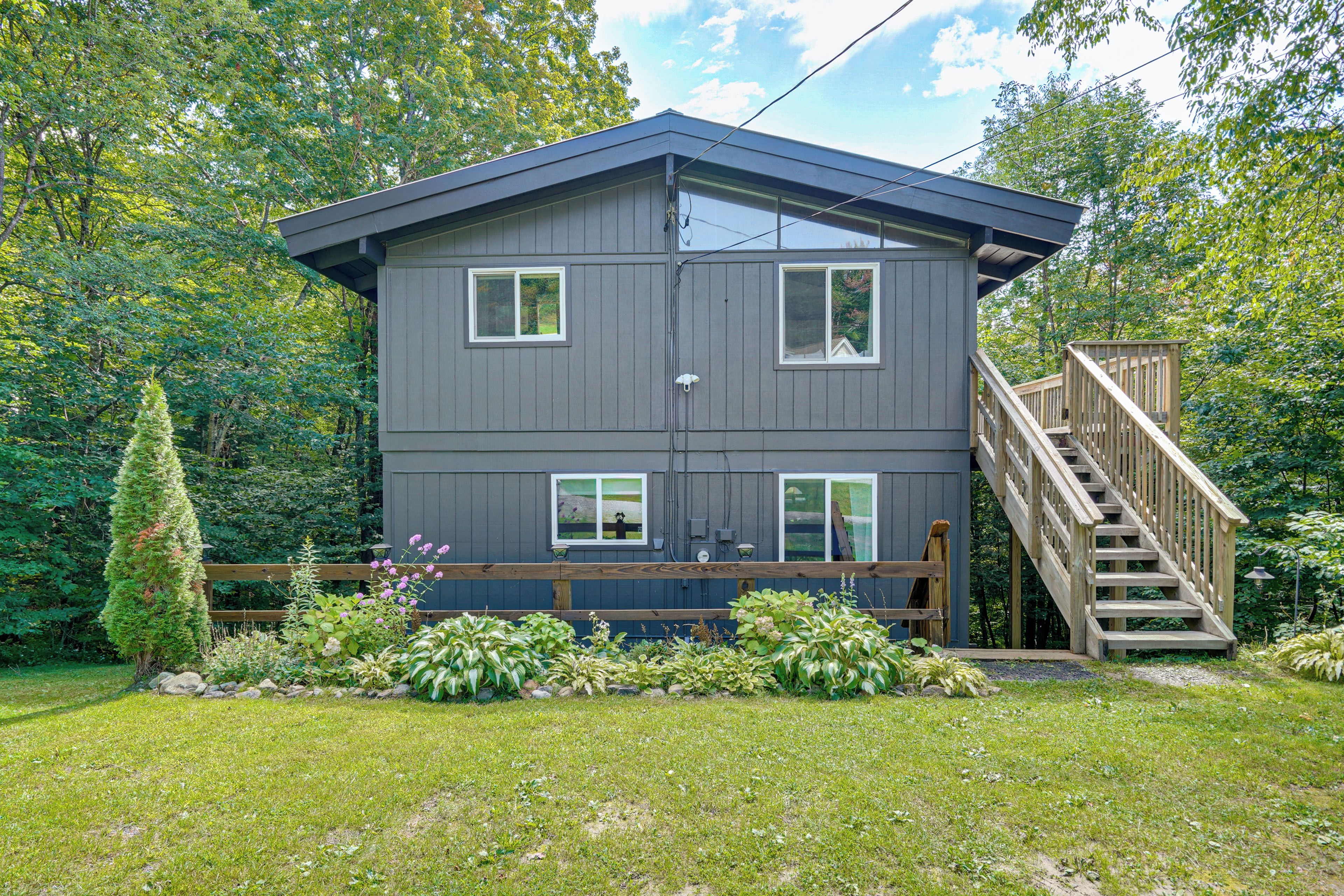 A two-story house with a deck and a staircase leading to the upper level.