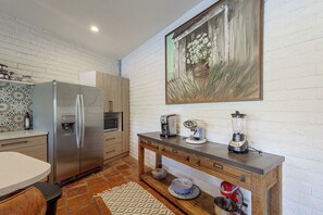 A modern kitchen with a stainless steel refrigerator, a microwave, a coffee maker, a blender, and a wooden cabinet.