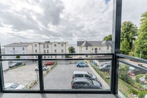 Blick aus einem Fenster auf einen Parkplatz mit mehreren Autos, ein Gebäude mit der Beschriftung 'Villas A SEGRESE' und einem klaren Himmel.