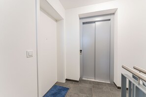 Ein Flur mit blauem Teppich, der zu einem geschlossenen Fahrstuhl führt.