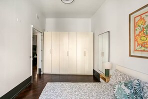 Ein Schlafzimmer mit einem Bett, einem Nachttisch, einem Kleiderschrank und einem Spiegel.