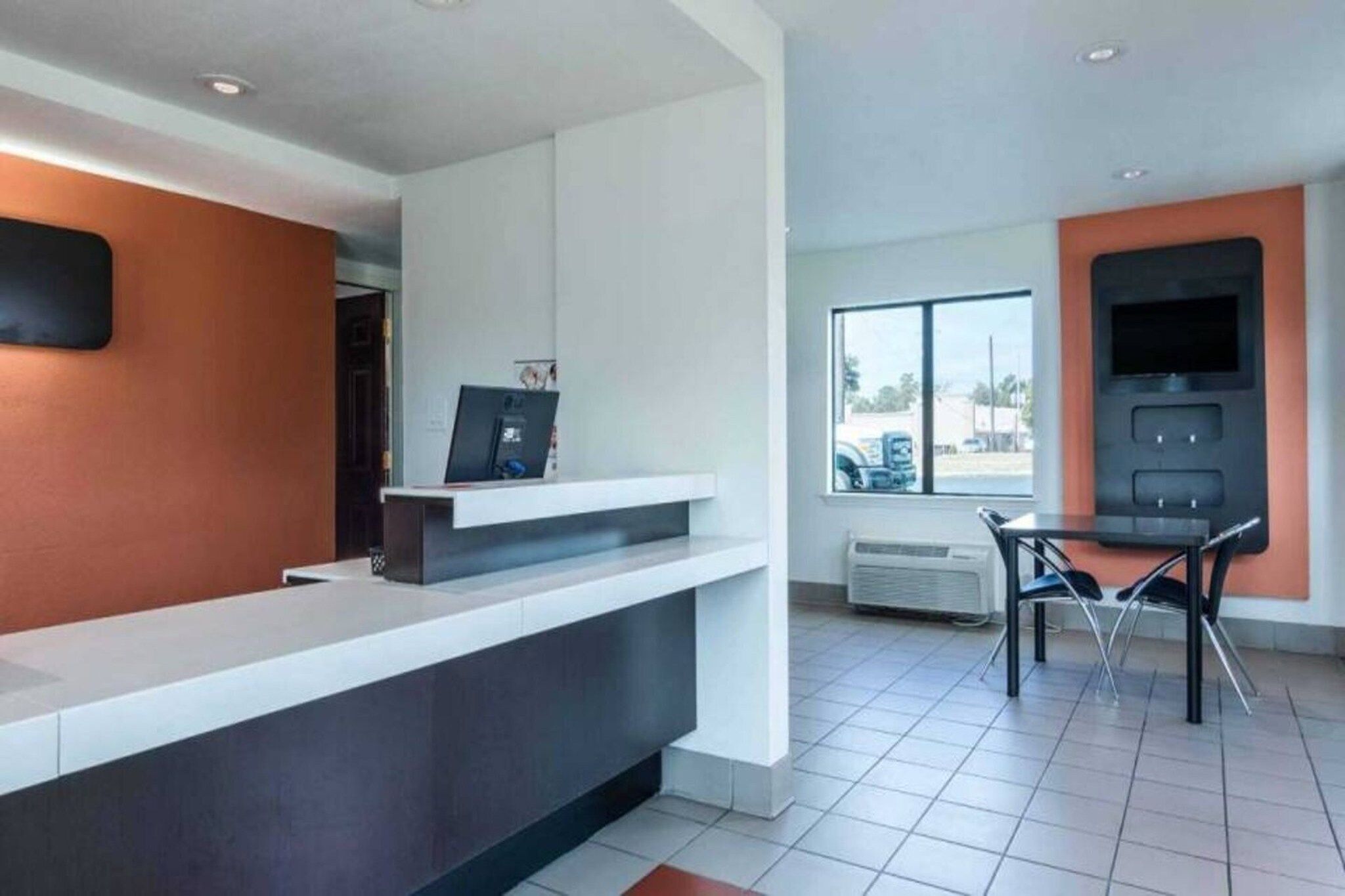A modern reception area with a counter, a television, and a window with a view of the outside.