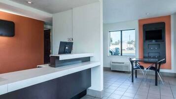 A modern reception area with a counter, a television, and a window with a view of the outside.