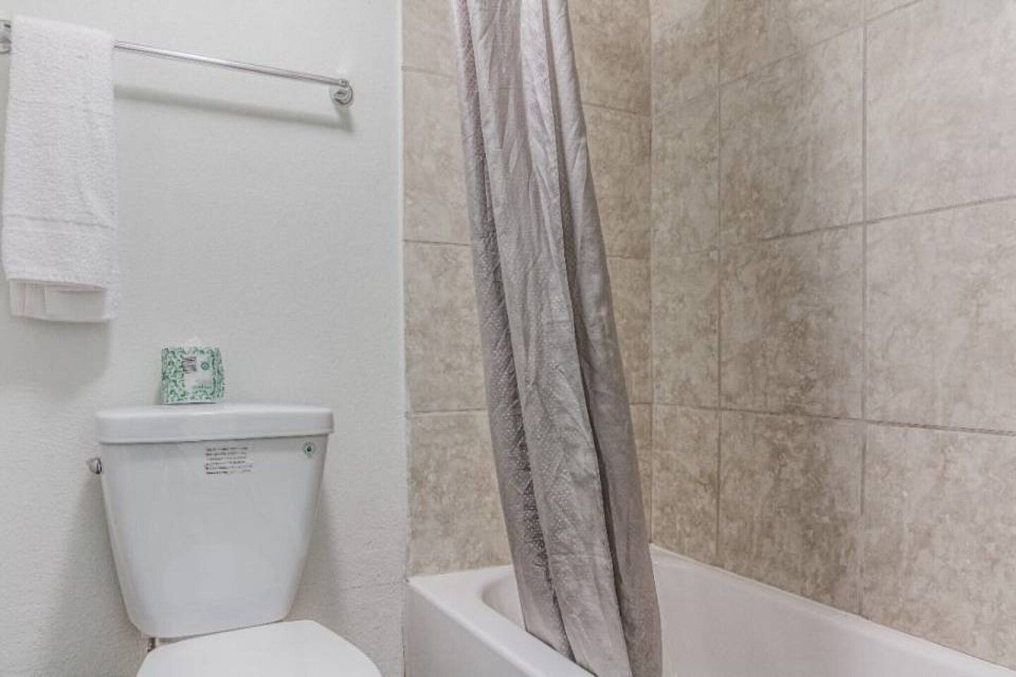A bathroom with a toilet, a towel rack, and a shower curtain.
