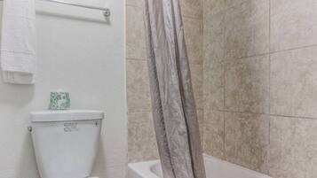 A bathroom with a toilet, a towel rack, and a shower curtain.