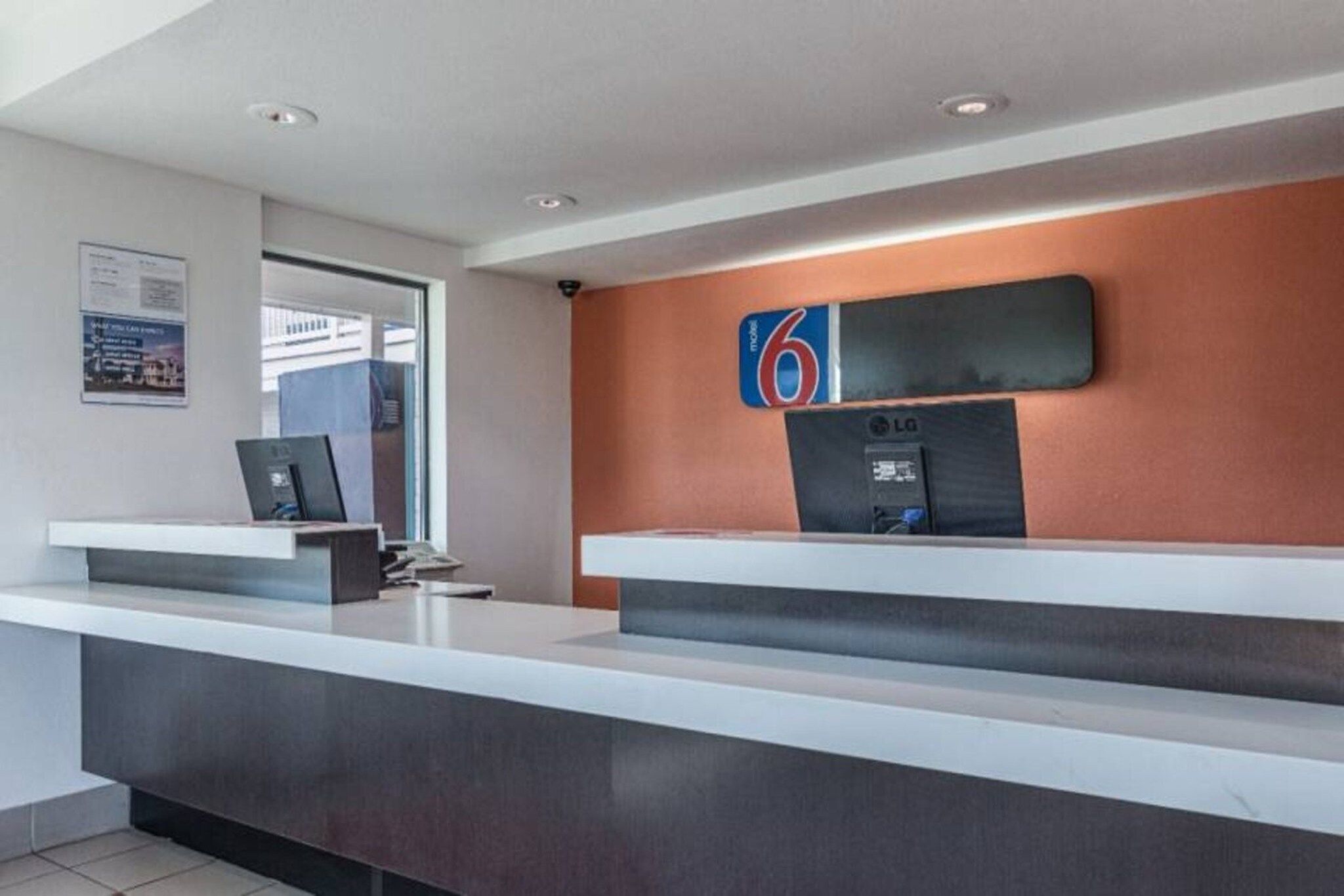 A modern reception desk with a flat-screen monitor, a laptop, and a sign indicating the number 6.