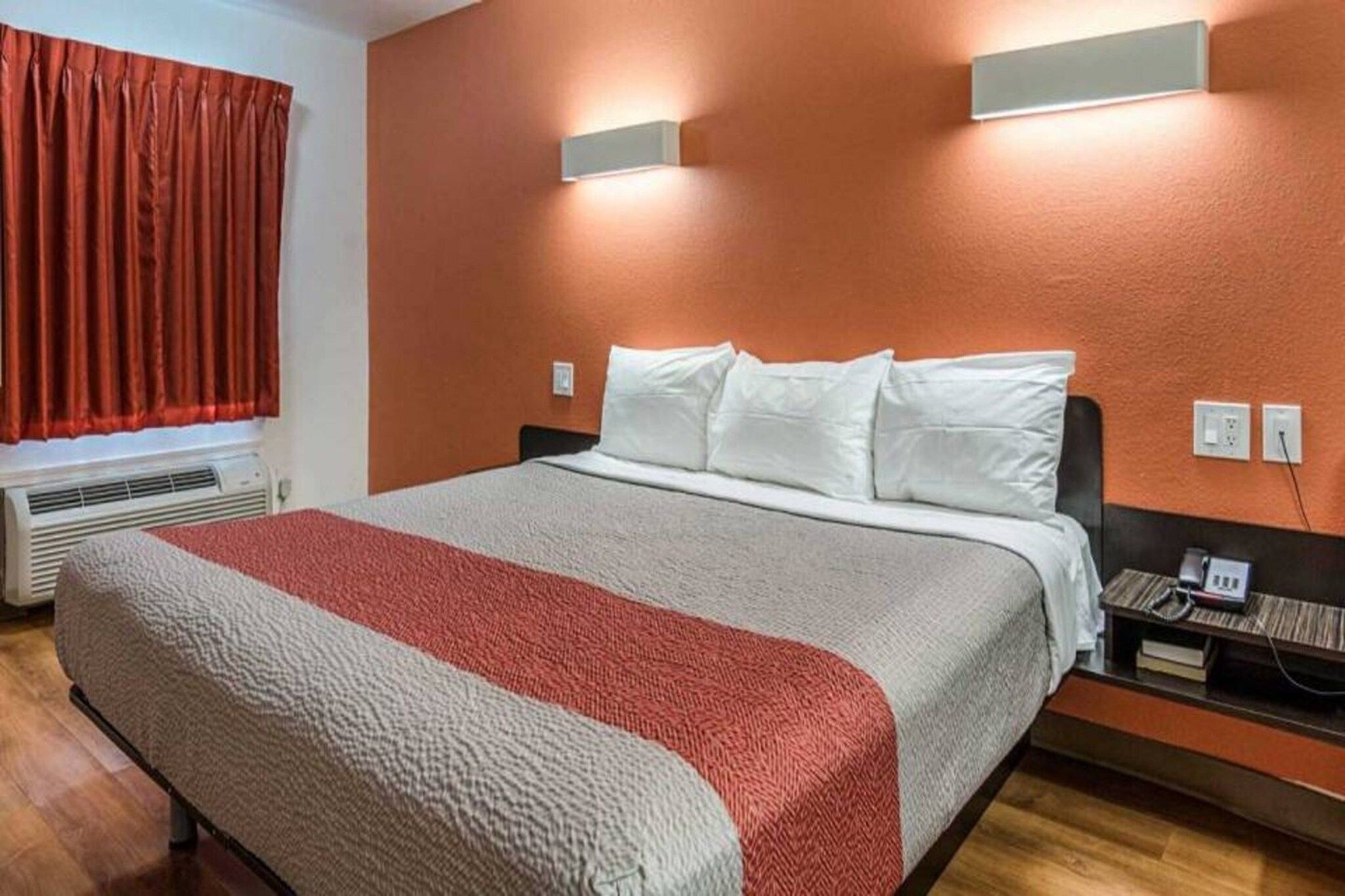 Ein Hotelzimmer mit einem Bett, einem Nachttisch mit Telefon und einer Wandleuchte.