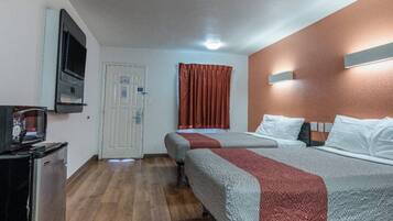 Une chambre d’hôtel avec deux lits, une télévision, une porte et une fenêtre avec des rideaux.