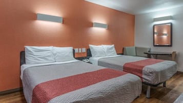 Quarto de hotel com duas camas, uma mesa pequena e uma cadeira.