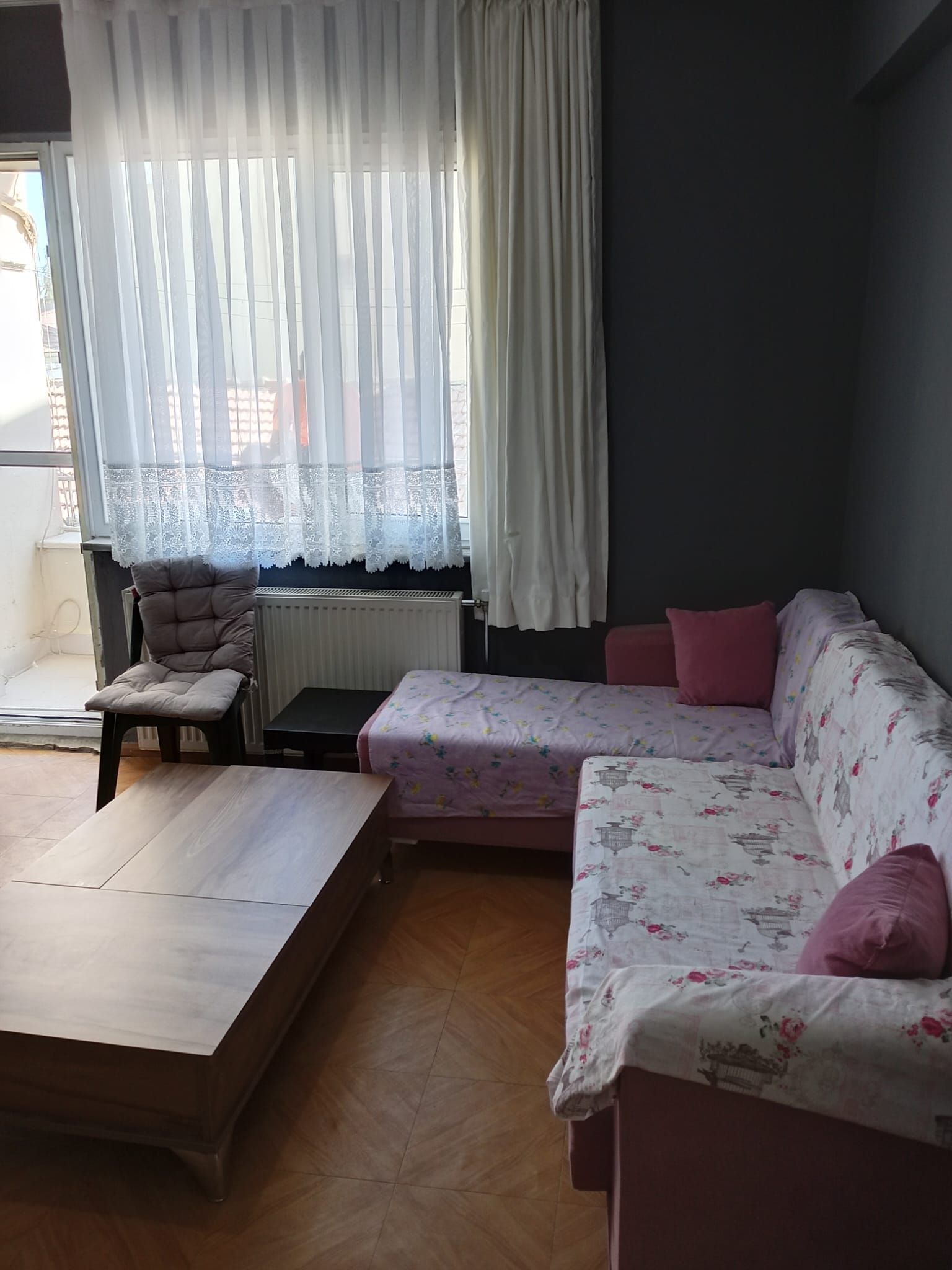 Una habitación con una cama, una silla, una mesa y una ventana con cortinas.