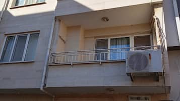 Un immeuble à plusieurs étages doté de balcons, d’une enseigne indiquant « APPARTEMENTS INANILAR » et d’une fenêtre ornée de motifs en métal.