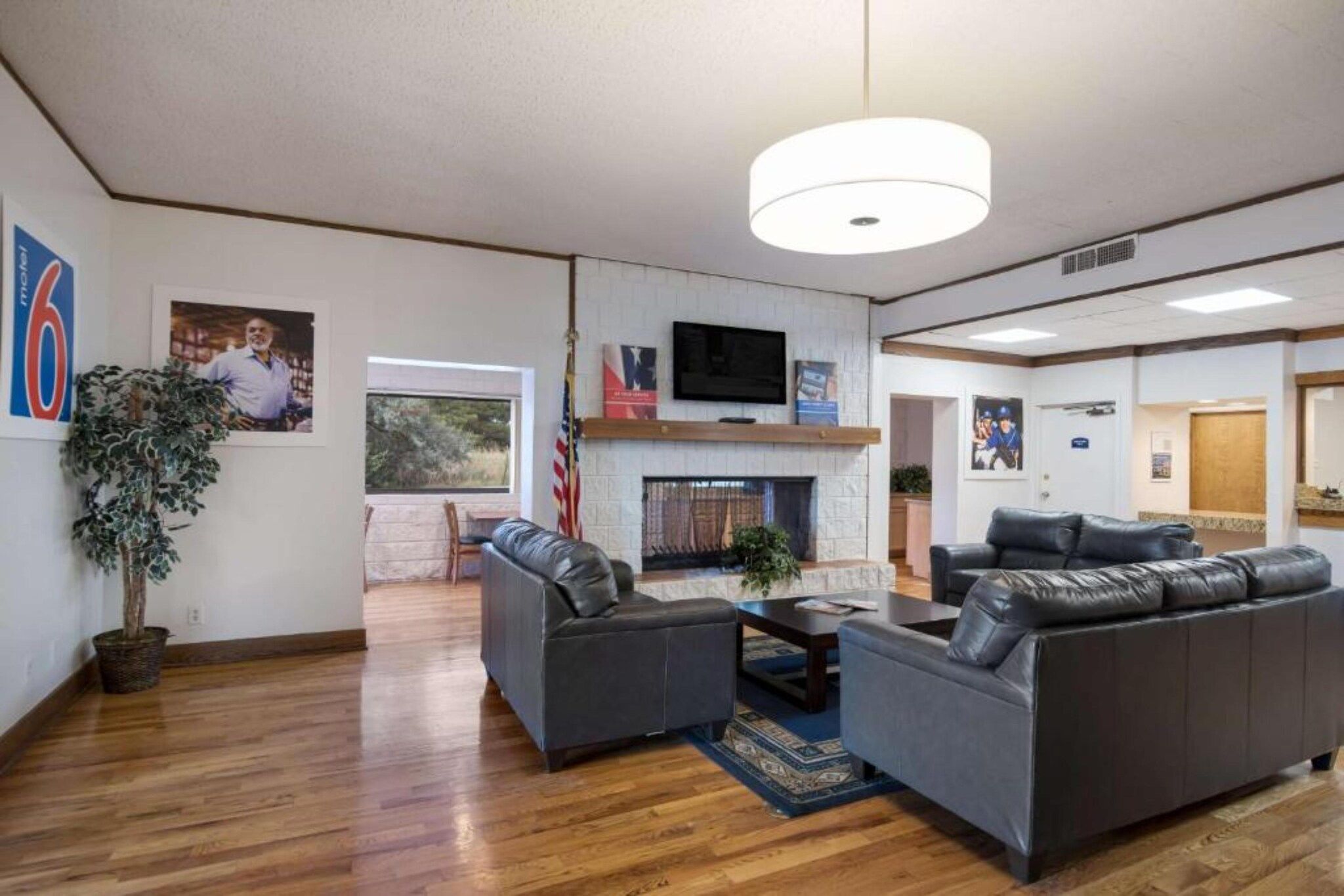 A spacious lobby with a fireplace, leather sofas, a television, and a large window.