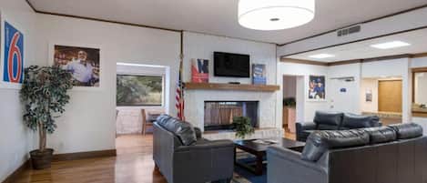A spacious lobby with a fireplace, leather sofas, a television, and a large window.