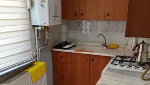 Eine Küche mit Holzschränken, einer weißen Arbeitsplatte, einem Spülbecken, einem Herd und einer Heizung.